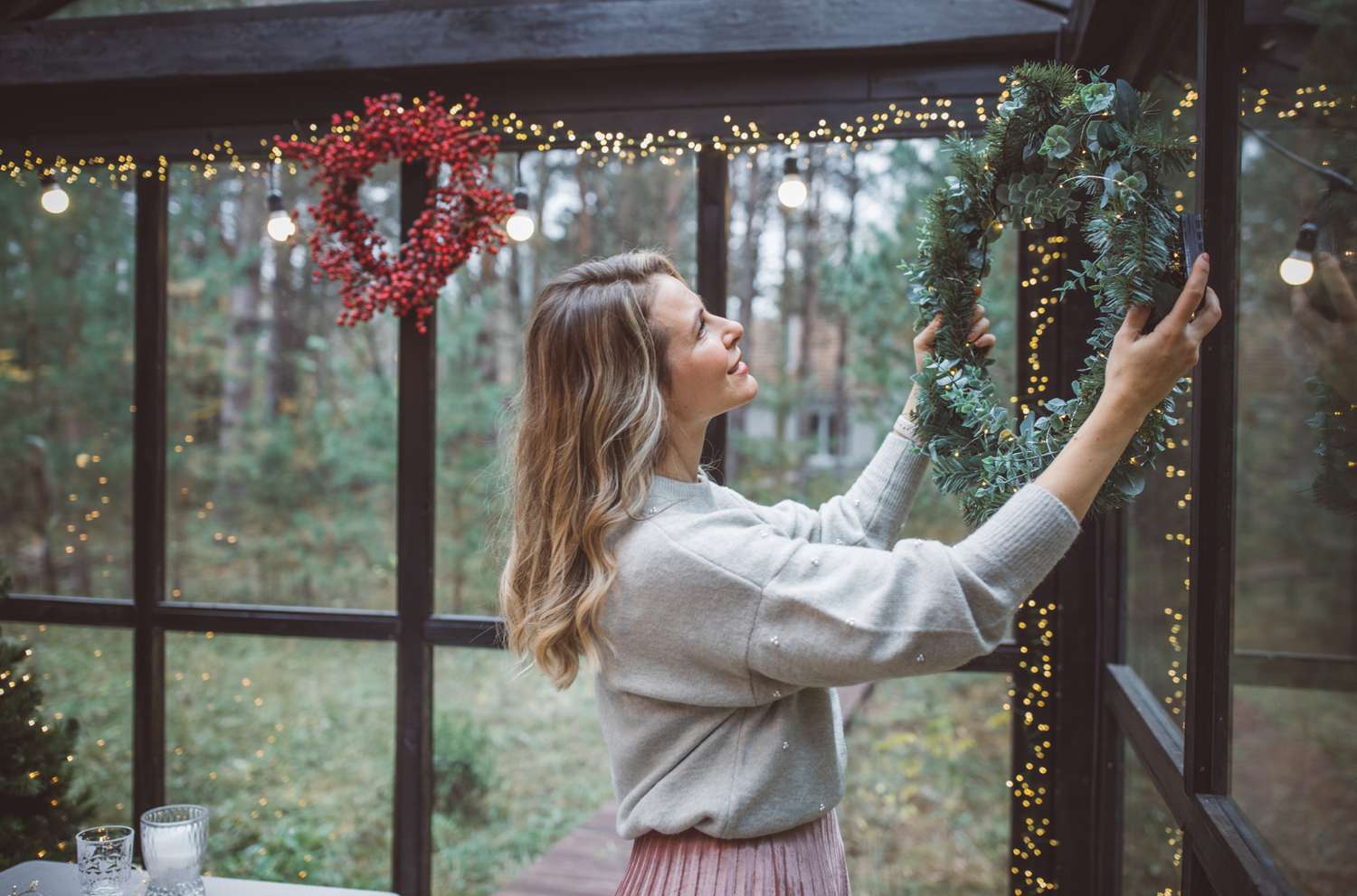A woman hangs a wreath on a window