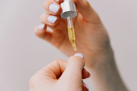 woman applying oil to nails