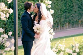 bride and groom kissing under flower arch