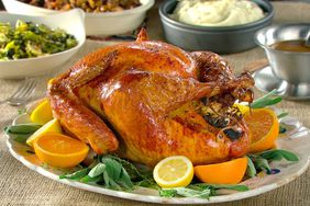 citrus and herb roasted turkey on platter with mashed potatoes on a nearby plate