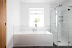 A general interior view of a tiled and painted bathroom with bathtub and glass shower.