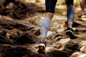 person wearing compression socks running along rocks