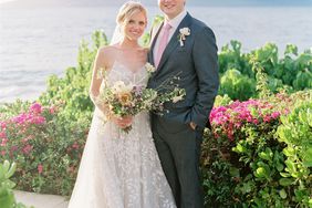 bride and groom posing in front of ocean surrounded by pink flowers