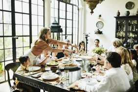 woman serving family a meal during at-home dinner party