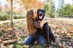 girl hugging dog during fall