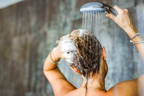 Back view of a woman washing her hair with a shampoo in bathroom.