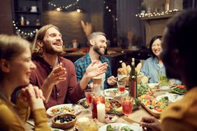 Dinner party scene of people laughing while eating
