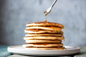 Stack of perfectly cooked pancakes being drizzled with honey