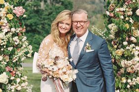wedding couple smiling under floral arch