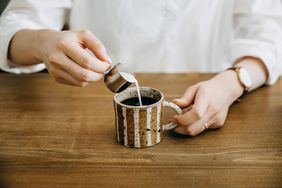 Person pouring milk into cup of coffee