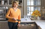 Martha Stewart in orange sweater standing in kitchen
