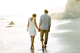 couple holding hands on beach outdoor engagement photos