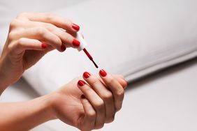 woman painting nails red nail polish