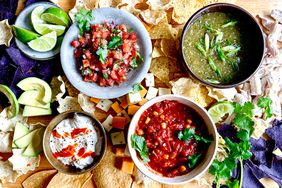 Salsa board with chips, cilantro, lime and sour cream