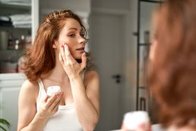 Woman using face cream in the bathroom