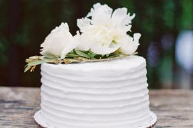 simple white wedding cake with florals on wooden table