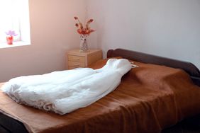 wedding dress displayed on bed