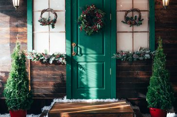 Porch with wooden doors and a threshold with Christmas decor.